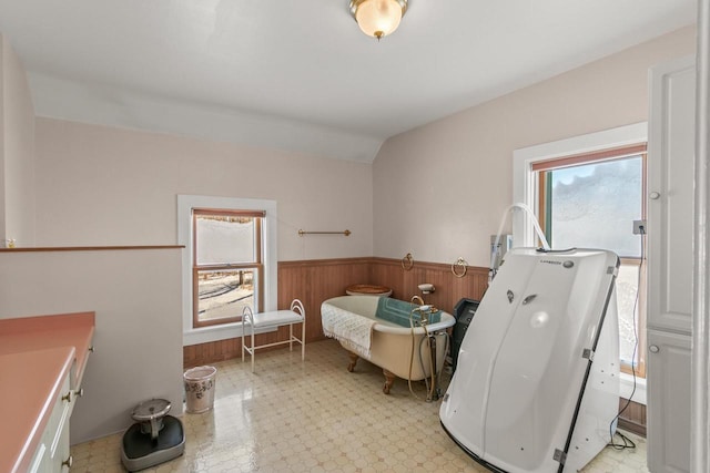 bathroom with a wainscoted wall, wood walls, vaulted ceiling, and tile patterned floors