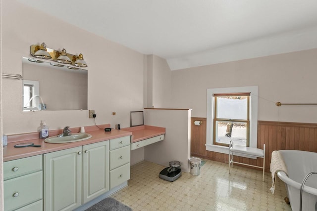 full bathroom featuring vaulted ceiling, wooden walls, wainscoting, and a healthy amount of sunlight