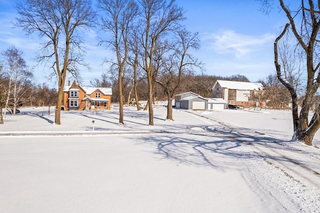 yard layered in snow with a detached garage and an outdoor structure