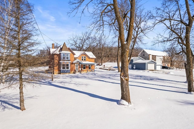 yard layered in snow featuring a garage and an outbuilding