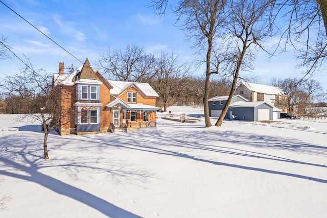 view of front of property featuring a garage, brick siding, a chimney, and an outbuilding