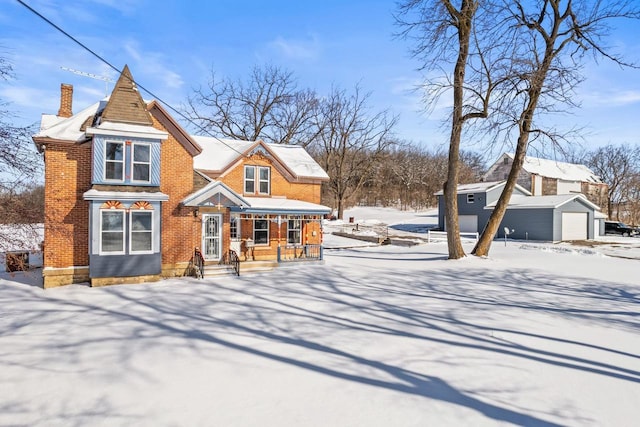 view of front of house featuring a detached garage, a chimney, an outbuilding, and brick siding