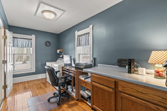 office area featuring baseboards, washer and clothes dryer, and light wood-style floors