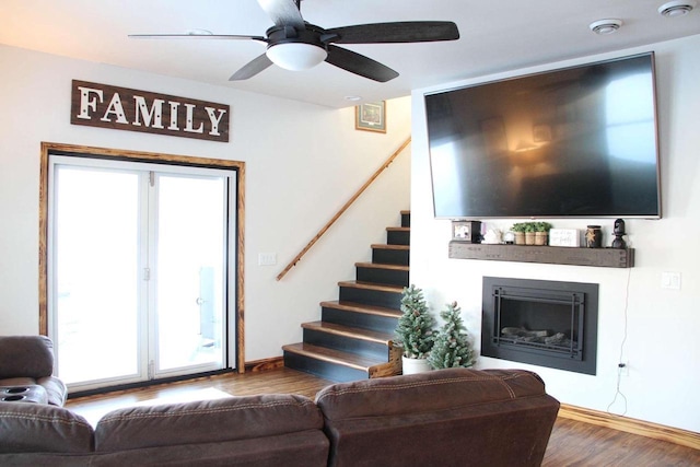 living room with a fireplace, stairway, ceiling fan, wood finished floors, and baseboards