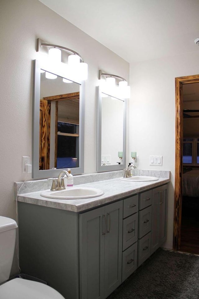 bathroom featuring toilet, double vanity, and a sink