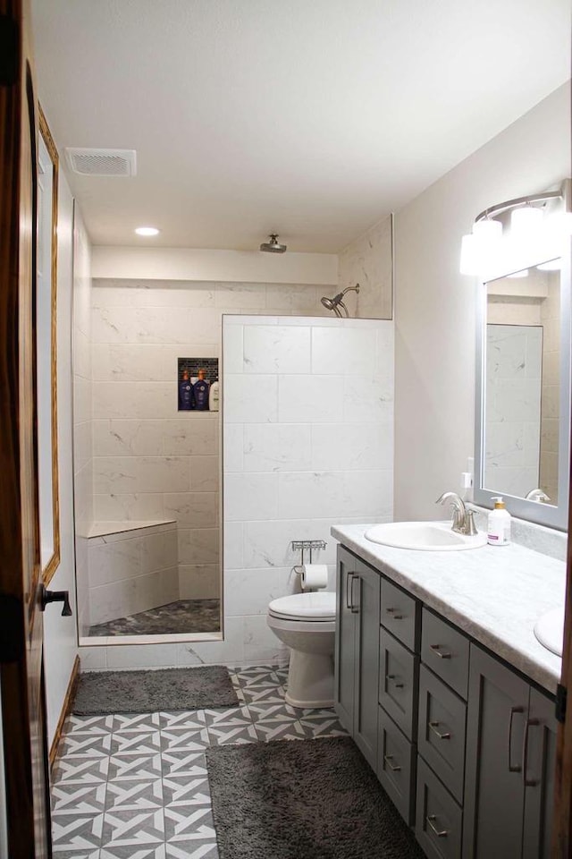 full bath featuring toilet, a sink, visible vents, double vanity, and walk in shower