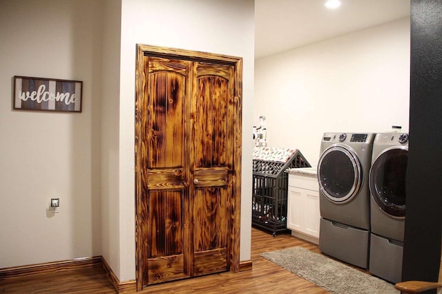 laundry room featuring cabinet space, washer and clothes dryer, and wood finished floors