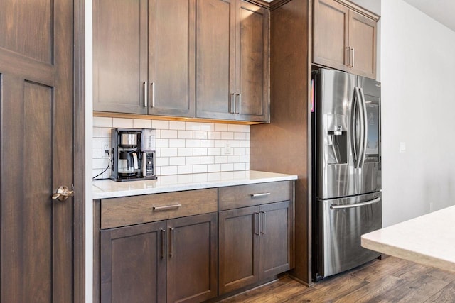 kitchen with light countertops, stainless steel fridge, dark wood finished floors, and backsplash