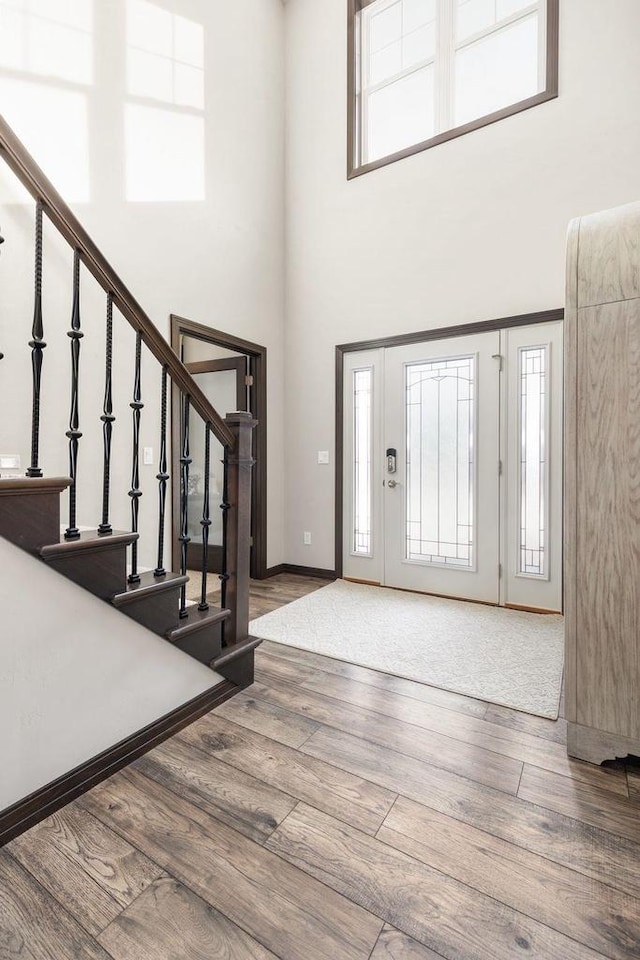 foyer entrance featuring stairs, a towering ceiling, and wood finished floors