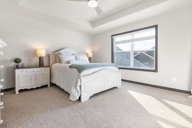 bedroom featuring a raised ceiling, light colored carpet, and baseboards