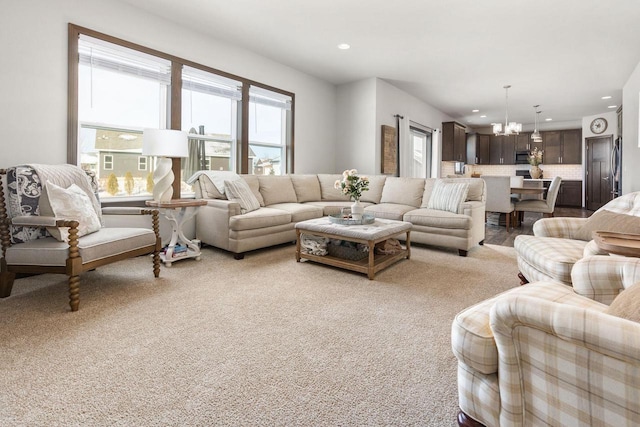 living area with recessed lighting, light colored carpet, and a notable chandelier