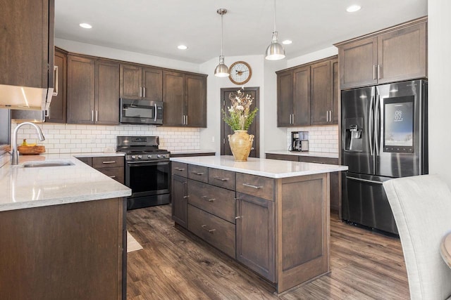 kitchen with appliances with stainless steel finishes, a center island, a sink, and dark brown cabinetry