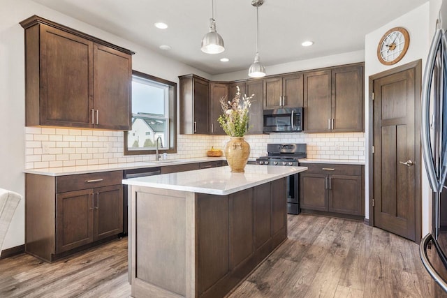 kitchen with appliances with stainless steel finishes, light countertops, dark brown cabinetry, and wood finished floors