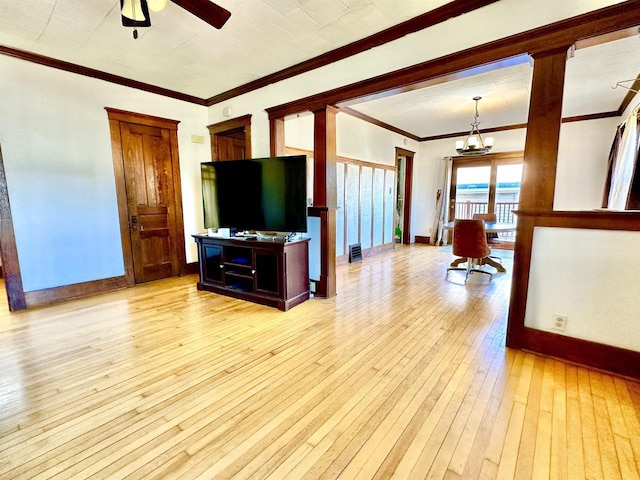 living room with light wood-type flooring, crown molding, baseboards, and ceiling fan with notable chandelier