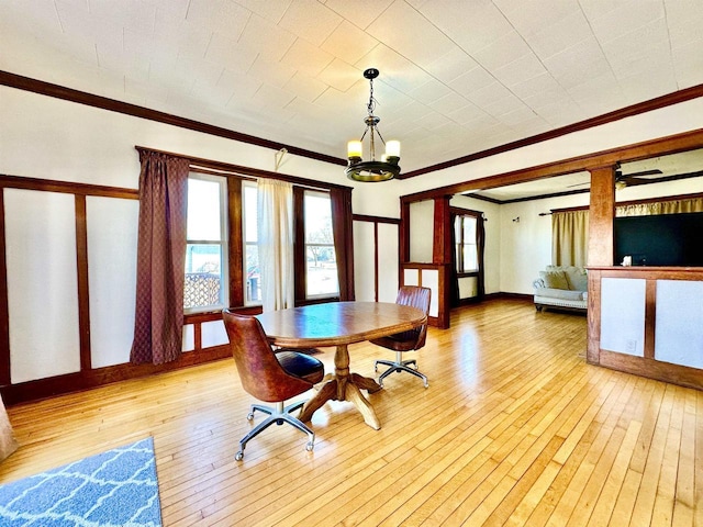 dining room with a chandelier, light wood finished floors, baseboards, and crown molding