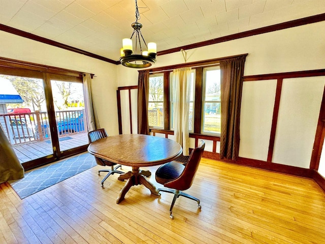 dining room with light wood finished floors, baseboards, a chandelier, and crown molding