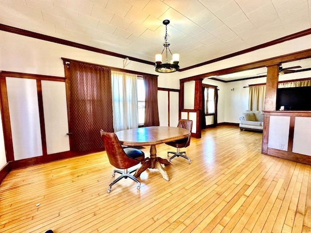 unfurnished dining area featuring a notable chandelier, light wood-type flooring, baseboards, and crown molding