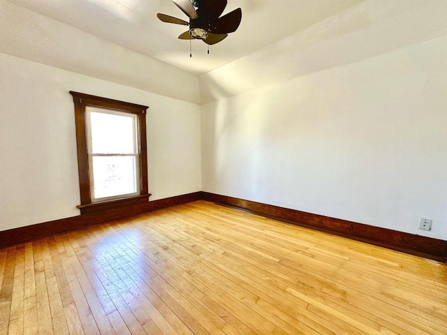 empty room featuring light wood-type flooring, ceiling fan, baseboards, and lofted ceiling