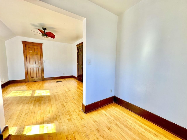 unfurnished room with a ceiling fan, lofted ceiling, light wood-style flooring, and baseboards