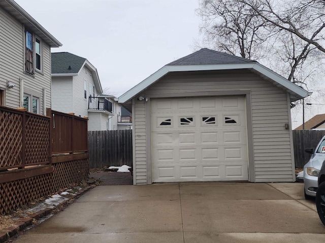 detached garage featuring driveway and fence