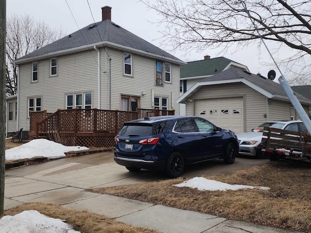 exterior space featuring a deck, driveway, a chimney, and a garage