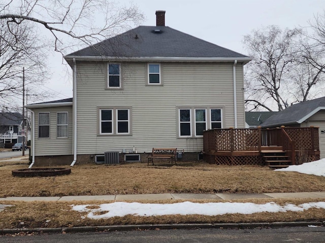 snow covered rear of property featuring a deck, cooling unit, roof with shingles, and a chimney