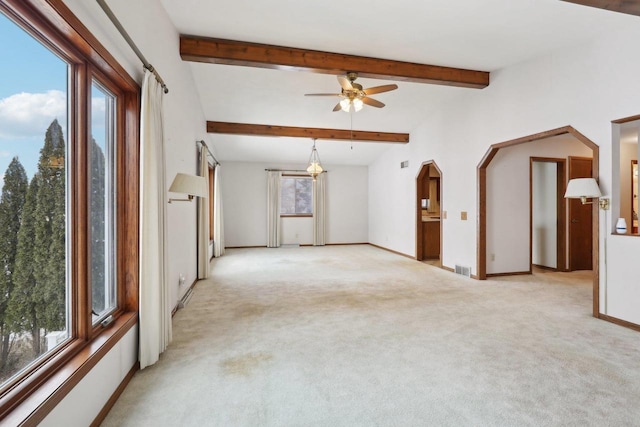 spare room with vaulted ceiling with beams, arched walkways, light colored carpet, a ceiling fan, and baseboards