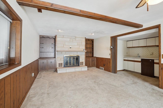 unfurnished living room featuring a wainscoted wall, a fireplace, wood walls, and light colored carpet