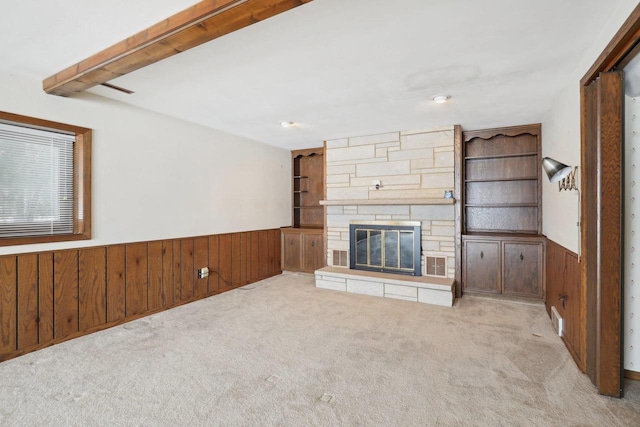 unfurnished living room with carpet floors, a wainscoted wall, and wooden walls