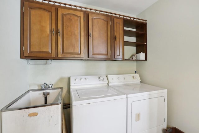 washroom with cabinet space, a sink, and independent washer and dryer