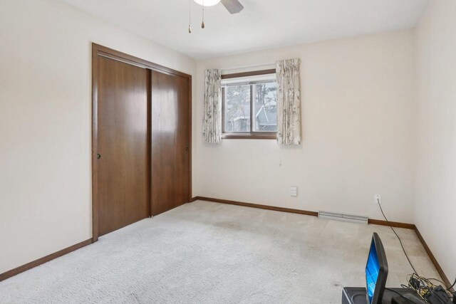 unfurnished bedroom featuring light carpet, baseboards, baseboard heating, and a closet