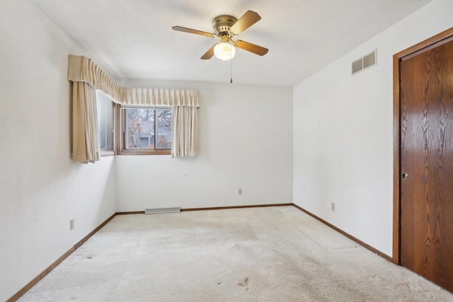 unfurnished room featuring carpet floors, visible vents, baseboards, and a ceiling fan