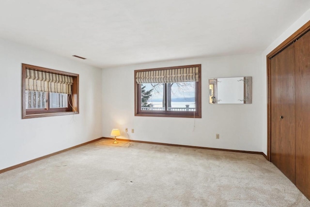 spare room with light carpet, baseboards, and visible vents