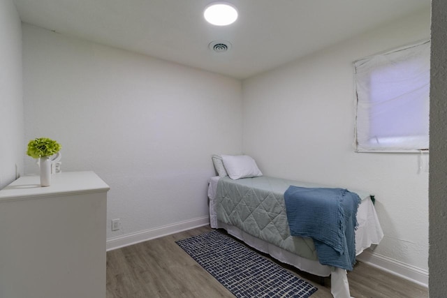 bedroom featuring baseboards, visible vents, and wood finished floors