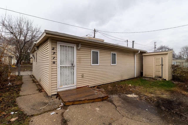 back of house with a storage unit, fence, and an outdoor structure