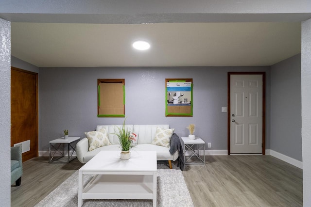 living room with baseboards, visible vents, and light wood finished floors