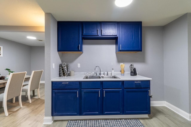 kitchen featuring blue cabinets, light wood-style floors, light countertops, and a sink