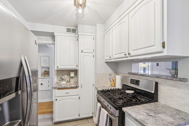 kitchen with visible vents, white cabinets, appliances with stainless steel finishes, light wood-type flooring, and decorative backsplash