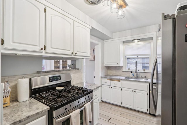 kitchen with backsplash, appliances with stainless steel finishes, white cabinets, and a sink