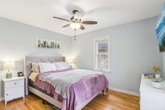 bedroom with light wood finished floors, a ceiling fan, and baseboards