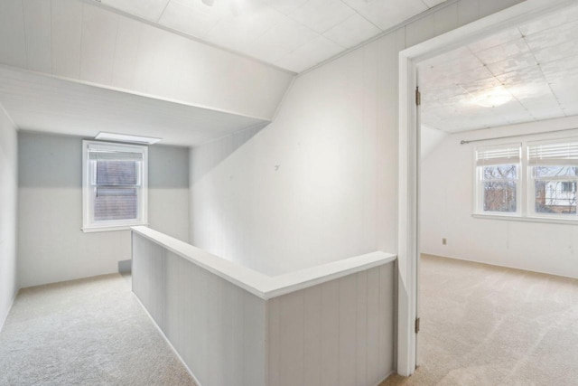 hallway featuring an upstairs landing and light colored carpet