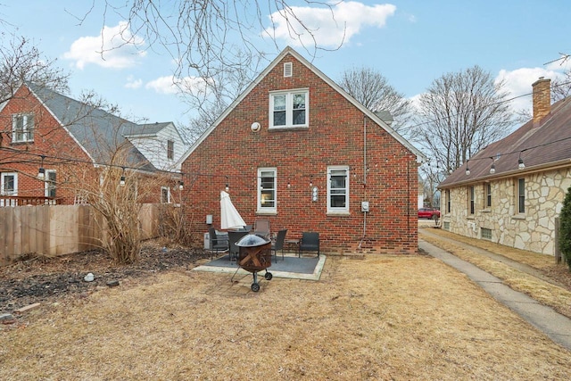 rear view of property with an outdoor fire pit, brick siding, a patio, and fence