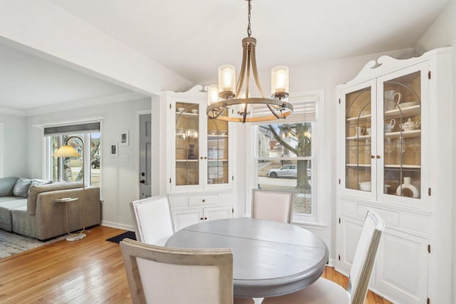 dining area with crown molding, baseboards, light wood-style flooring, and an inviting chandelier