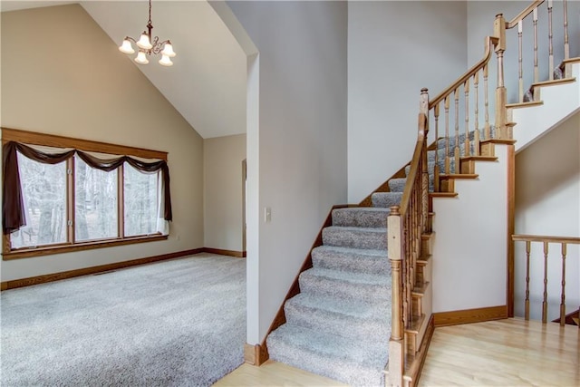 stairway featuring high vaulted ceiling, a notable chandelier, baseboards, and carpet flooring