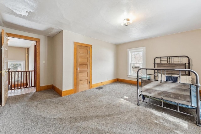 carpeted bedroom with visible vents, multiple windows, and baseboards