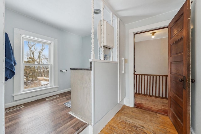 hallway with wood finished floors, visible vents, and baseboards