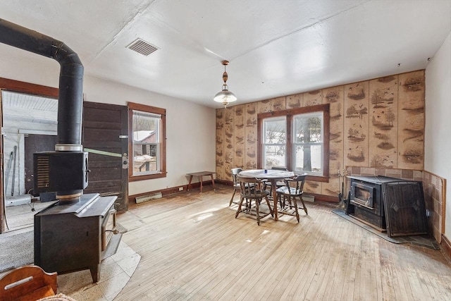 dining space with visible vents, wood-type flooring, a wood stove, and baseboards