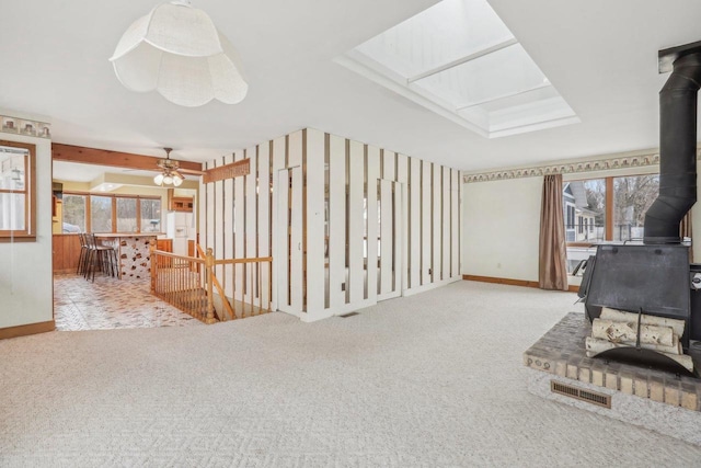 interior space featuring a skylight, a wood stove, visible vents, and plenty of natural light