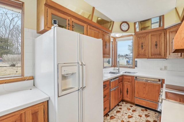 kitchen featuring a healthy amount of sunlight, paneled dishwasher, white fridge with ice dispenser, and a sink