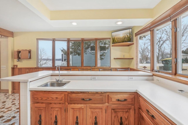 kitchen featuring brown cabinets, light countertops, a sink, and recessed lighting